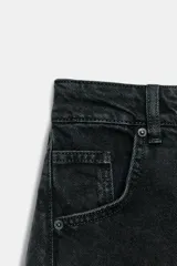 Pantalón de jean negro de tiro bajo, corte amplio tipo balloon, con cinco bolsillos y cierre frontal con cremallera y botón.