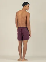 Short de baño color bordó con cintura elástica ajustable, bolsillos laterales y trasero con cierre, y suspensor de malla hipoalergénico. Cuenta con tejido de secado extra rápido y protección UV 50.