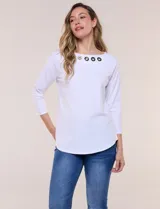 Remera blanca de algodón con elastano, de corte semi holgado, escote bote con ojalillos metálicos frontales, mangas tres cuartos raglán y ruedo asimétrico curvado.