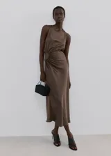 Vestido midi de satén color marrón, sin mangas y con cuello redondo. Presenta un diseño con frunces laterales en la cintura que crean un efecto drapeado y una silueta entallada.