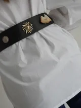 Cinto ancho de cuero marrón con apliques metálicos decorativos en forma de sol, caballo y herraduras, acompañado de tachas.