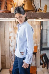 Camisa de manga larga con diseño a rayas verticales celestes y blancas, cuello mao y detalles de volados en los puños.