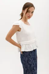 Remera blanca de lyocell y algodón, con mangas cortas con volados y frunce en la cintura.