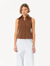 Camisa sin mangas color marrón, confeccionada en tela de punto lisa, de corte regular. Lleva cartera con broches y pinzas que entallan la prenda.