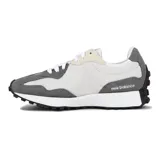 Championes urbanos New Balance modelo 327, con diseño retro inspirado en los años 70. Presentan una combinación de paneles de gamuza gris y nylon blanco, con el logo 'N' característico en el lateral y suela de goma con relieve extendido hacia el talón.