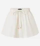 Minifalda blanca de poliéster, corte baloné, con elástico y lazo ajustable en la cintura.