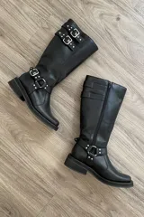 Bota alta de cuero negro con caña alta y hebillas plateadas.