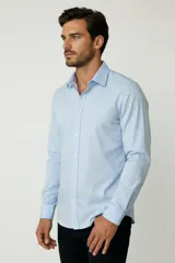 Camisa blanca de algodón, de diseño holgado y manga larga, con cuello camisero y cierre frontal de botones.