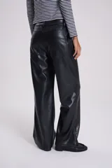 Pantalón de cuero sintético negro, estilo jeanero con tiro bajo, corte recto/flare y bolsillos delanteros y traseros.