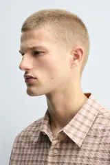 Camisa de corte relajado confeccionada en tejido fluido con algodón. Presenta un diseño de cuadros, cuello solapa, manga larga con puño abotonado, bolsillo plastrón en el pecho y cierre frontal con botones.