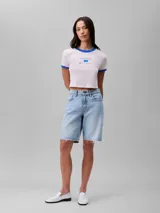 Remera cropped de manga corta color rosa pálido, con cuello redondo y ribetes azules. Estampado frontal con el logo de Calvin Klein y la inscripción 'New York City' en azul.
