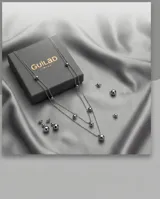 Set de joyería compuesto por un collar de tres cadenas finas con dijes de esferas metálicas y un par de aros colgantes con diseño de esfera. Fabricado en acero italiano.