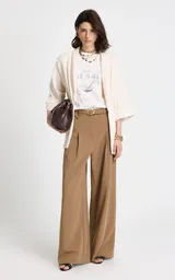 Pantalón sastrero de tiro alto en color camel, con corte recto y pernera ancha. Presenta pliegues frontales, bolsillos laterales y cierre frontal con cremallera y gancho. Incluye un cinturón a juego con hebilla metálica ovalada.