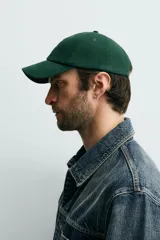 Gorra de seis paneles confeccionada en tejido de algodón, color verde oscuro, con parche frontal de letra P en color crema y ajuste posterior.