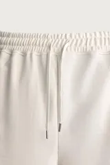 Bermuda estilo jogger de ajuste relajado, color negro, confeccionada en tejido interlock de algodón. Cuenta con cintura elástica ajustable mediante cordón, bolsillos delanteros tipo vivo y diseño liso.