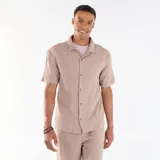 Camisa de manga corta de punto jacquard color beige, con cuello camisero y cierre frontal de botones.