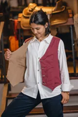 Chaleco reversible de lino, color naranja en el exterior y rayas finas en el interior, con cuello en V y cierre frontal de botones.