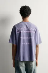 Camiseta relaxed fit de color gris con efecto lavado, cuello redondo y manga corta. Cuenta con un pequeño texto estampado en contraste en el pecho.