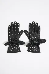 Par de guantes negros de cuero con lunares plateados y lazo decorativo en la muñeca.