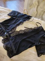 Conjunto de lencería compuesto por un top de encaje y microtul con escote profundo y una tanga regulable a juego. El top presenta mangas cortas de encaje y detalles de puntilla, mientras que la tanga combina microtul y encaje con forro de algodón.