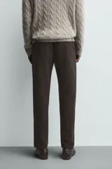 Pantalón chino de corte ajustado, color beige, con bolsillos laterales y bolsillos traseros de vivo. Cuenta con cierre frontal de cremallera y botón.