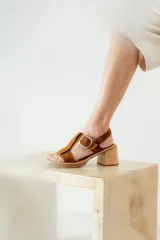 Sandalias de cuero color marrón con tiras anchas y hebilla plateada. Taco de madera.