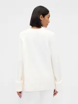 Buzo de tejido de punto con cuello redondo, mangas largas y diseño holgado.