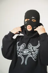 Hoodie negro oversize de algodón con capucha y pasamontañas desmontable con cierre. Presenta estampa en plastisol en el pecho y en ambas mangas.