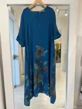 Vestido midi azul petróleo con estampado floral pintado, escote en V y mangas cortas con vuelta.