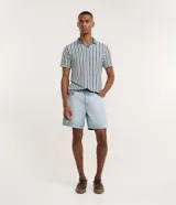 Bermuda de jean corte loose, color azul claro con lavado desgastado, cuenta con bolsillos laterales y traseros, cierre frontal con botón y bragueta, y pasacintos.