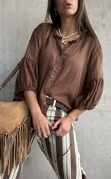 Camisa oversize color chocolate con cuello con volados, mangas abullonadas y cierre frontal con botones.