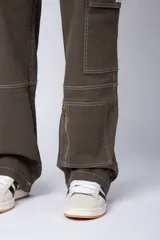 Pantalón tipo carpintero de corte relaxed fit y tiro medio, confeccionado en denim negro con costuras a contracolor en blanco. Presenta múltiples bolsillos cargo laterales, un bolsillo con cierre en la parte inferior y presillas utilitarias.
