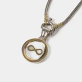 Conjunto compuesto por cadena de eslabones tipo serpiente en plata y oro, con dije circular que presenta el símbolo de infinito en oro sobre una base de nácar.