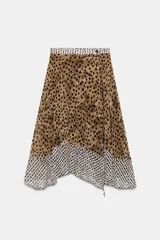Falda midi de tiro alto con bajo asimétrico y cierre frontal cruzado con botón. Presenta un diseño que combina estampado de lunares y animal print.