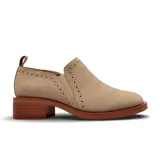 Zapato casual tipo botineta de gamuza en color beige, con diseño de perforaciones decorativas tipo brogue y elástico lateral. Presenta un taco cuadrado bajo de madera y suela a tono.