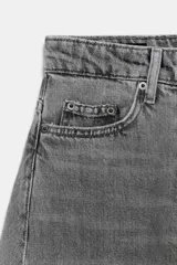 Jeans de tiro medio con diseño de pierna tipo balloon y largo al tobillo. Presenta cinco bolsillos, cierre frontal con cremallera y botón, y un acabado con efecto lavado.