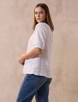 Blusa blanca de tejido calado, marca Sabrina Lauren. Cuello a la base y abertura central con botones.