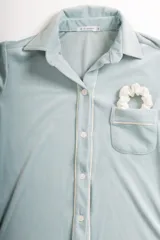 Pijama de dos piezas color rosa pálido, confeccionado en terciopelo. La camisa es de manga larga con botones frontales y bolsillo en el pecho. El pantalón es de corte recto con cintura elástica.