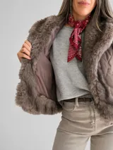 Chaleco acolchado color marrón con diseño matelassé y amplias solapas de piel sintética en tono chocolate. Presenta un corte recto y sin mangas, ideal para superposiciones.