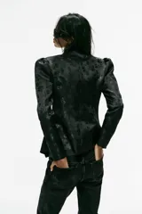 Blazer entallado de color negro con diseño jacquard floreado, cuello mao, manga larga abullonada y cierre frontal cruzado con alamares.