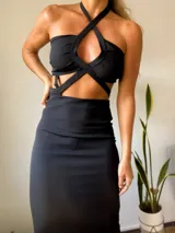 Vestido negro con escote halter y diseño cut-out en la cintura.