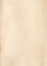 Camisa de lino color beige, de diseño recto con cuello camisero, manga larga con puños abotonados, bolsillo de parche en el pecho y cierre frontal de botones.