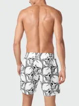 Short de baño blanco con estampado de calaveras negras y rayas horizontales en la parte inferior.