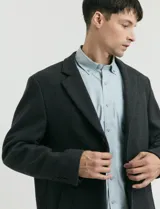 Sobretodo 3/4 de paño, color gris oscuro, con cuello solapa, cierre frontal de botones, manga larga y bolsillos laterales de ribete.