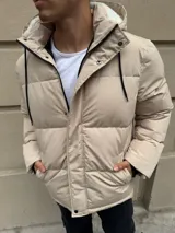 Campera puffer de nylon color beige, con diseño acolchado, cierre frontal con solapa y botones a presión. Cuenta con capucha desmontable forrada en corderito sintético y bolsillos laterales.