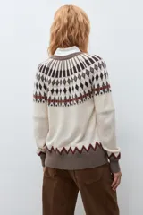 Cardigan de punto con diseño jacquard en tonos beige, marrón y rojo. Presenta cuello redondo, cierre frontal con botones y puños acanalados.