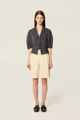 Camisa corta de popelina a rayas con mangas abullonadas, cuello solapa y cierre frontal con botón decorativo. Presenta un diseño con efecto plisado en el pecho y corte ajustado.