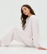 Conjunto de pijama compuesto por blusa de manga larga con cuello redondo y pantalón largo de corte regular. Confeccionado en plush suave, presenta detalles de encaje aplicados en los laterales de las mangas y de las piernas. El pantalón cuenta con cintura elástica para mayor comodidad.