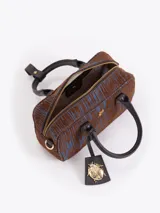 Cartera tipo baulito de cuero descarne vacuno con textura rayada en tonos marrón y azul. Presenta manijas cortas, cierre superior y un charm metálico dorado en forma de mariquita colgando de un tag de cuero. Incluye correa larga desmontable y regulable.