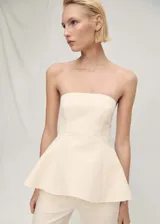 Top de corte peplum con diseño palabra de honor, sin mangas y cierre de cremallera en la parte posterior.